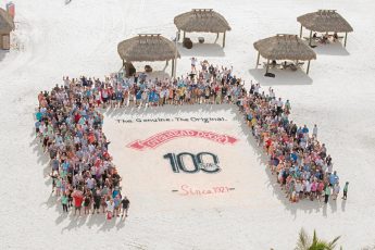 Overhead Door 100 years logo on the sand with the team standing around it